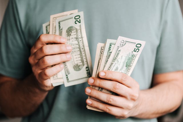 Man holding two stacks of cash, symbolizing Salary Withholding